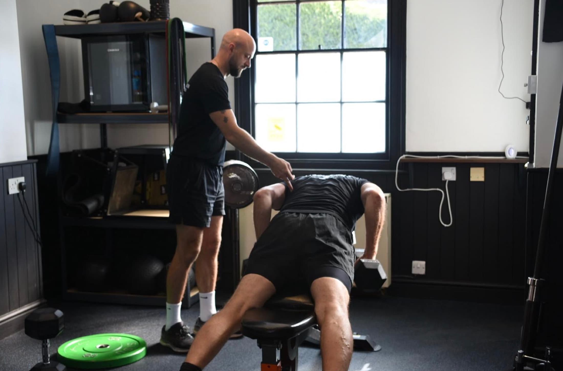 Michael Dennison coaching a client through a dumbbell row in his private studio